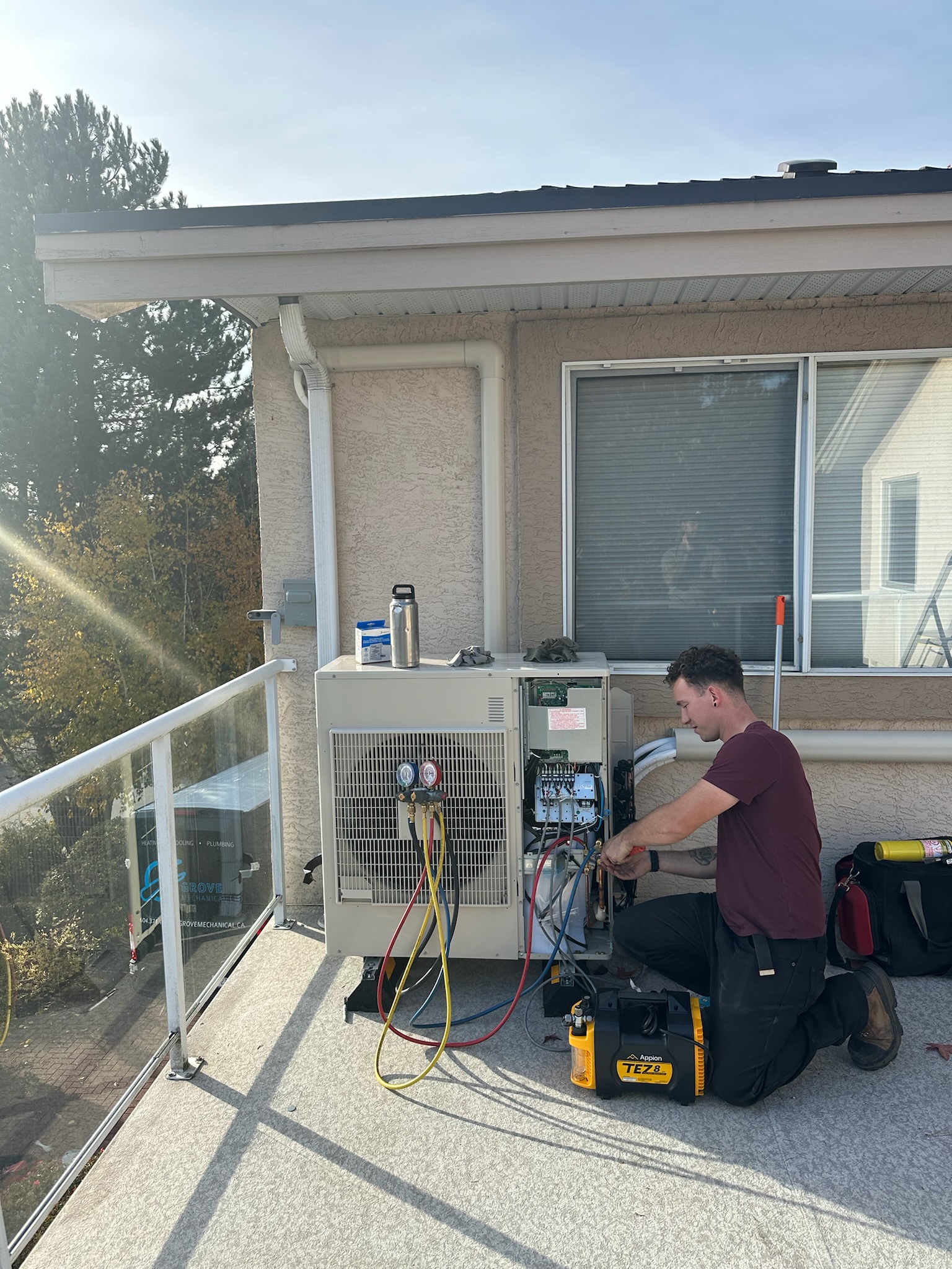 Grove technician servicing outdoor heat pump unit with refrigerant gauges